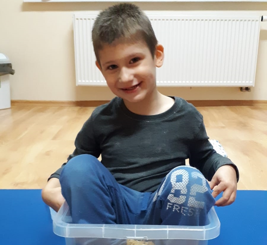 Urodzony z nieuleczalną wadą genetyczną GLUT1 sześcioletni Igorek Kamiński siedzący w plastikowym pojemniku podczas zabawy.