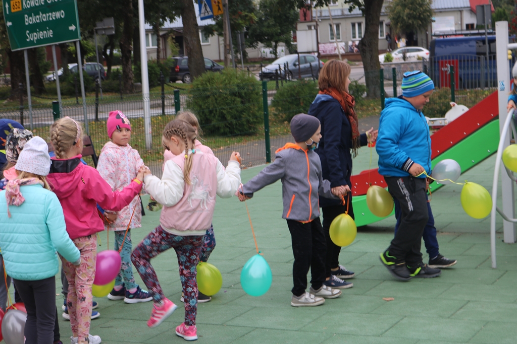 Zdjęcie przedstawia dzieci bawiące się balonikami na placu zabaw